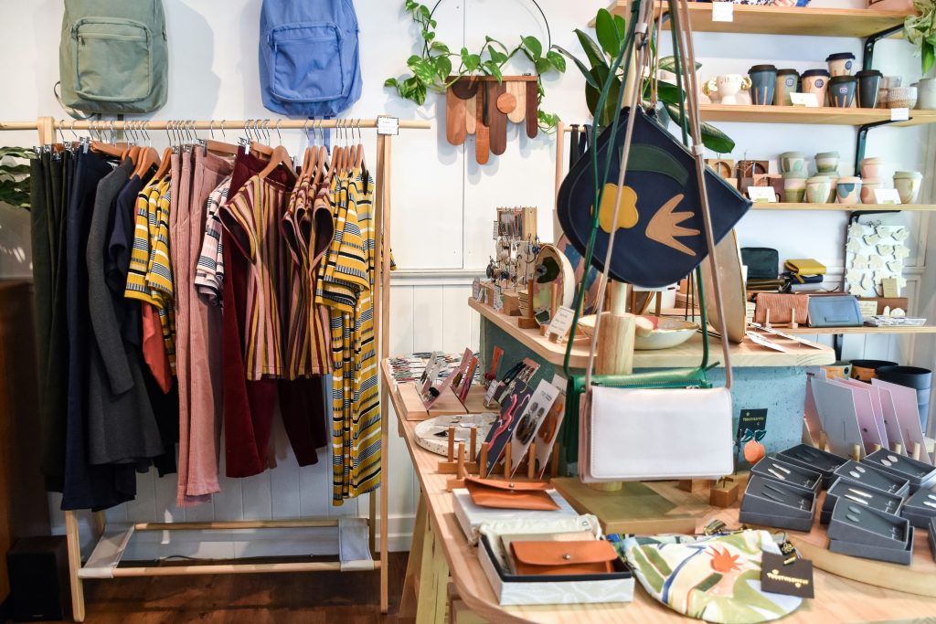 Racks overflowing with cozy sweaters, denim jackets, and stylish accessories in a welcoming neighborhood shop.