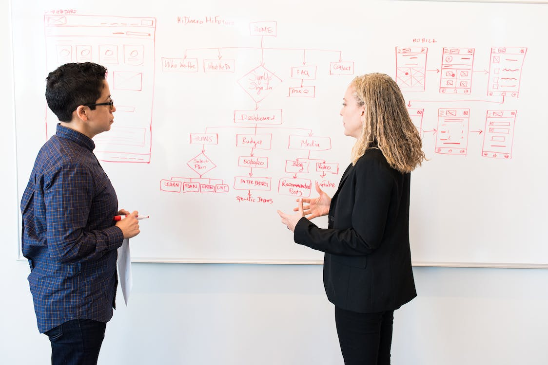 Two women social media managers discussing strategy in an office setting.